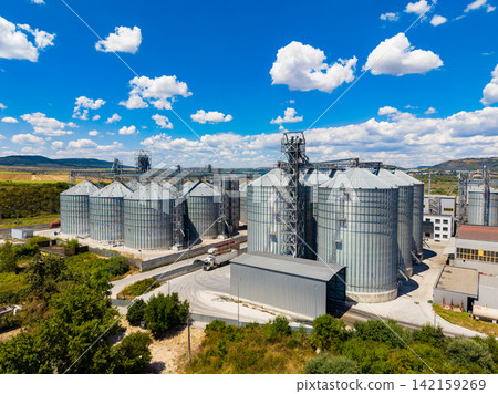 View of grain storage silos under bright blue sky with clouds during daytime View of grain storage silos under bright blue sky with clouds during daytime 142159269