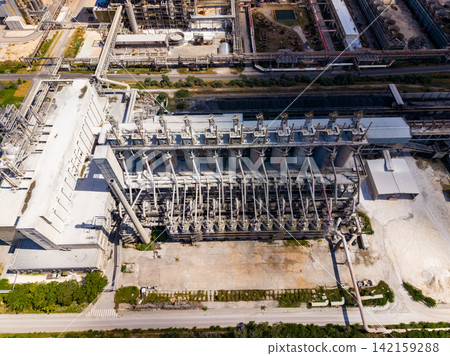 Industrial facility shows large machines and metal structures located in an industrial area during daylight hours Industrial facility shows large machines and metal structures located in an industrial area during daylight hours 142159288