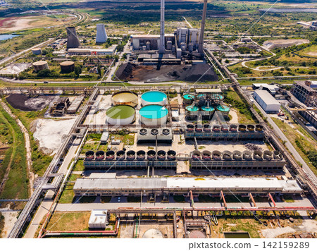 Industrial site with power plant and water treatment in a landscape with hills and water bodies Industrial site with power plant and water treatment in a landscape with hills and water bodies 142159289
