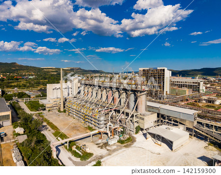 Large industrial facility under a blue sky with clouds during midday Large industrial facility under a blue sky with clouds during midday 142159300