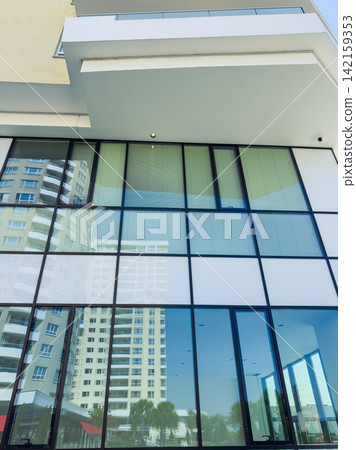 Building with large windows showing the reflection of nearby high-rise buildings in a sunny setting Building with large windows showing the reflection of nearby high-rise buildings in a sunny setting 142159353
