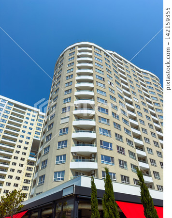 Building with multiple balconies under clear blue sky in an urban area Building with multiple balconies under clear blue sky in an urban area 142159355