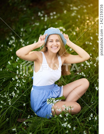 Woman, smile and portrait with flowers in field, nature and outdoors in countryside for happiness. Female person, hat and summer with dress on ground for relax, zen or calm in grassland for wellness 142159356