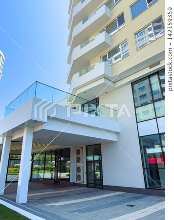 Building entrance with balcony in a modern structure during a sunny day Building entrance with balcony in a modern structure during a sunny day 142159359