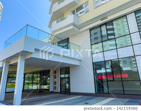 Building with large glass windows and modern design in a city area during bright day Building with large glass windows and modern design in a city area during bright day 142159360