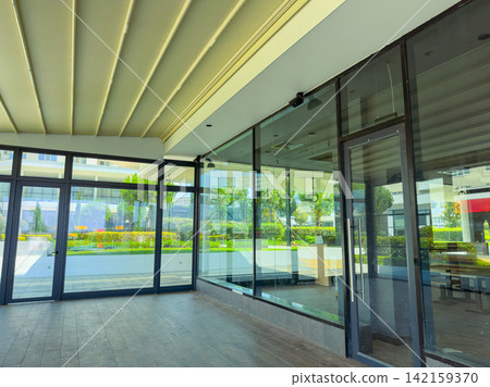 Large empty room with glass walls and view of garden in a modern building on a sunny day Large empty room with glass walls and view of garden in a modern building on a sunny day 142159370