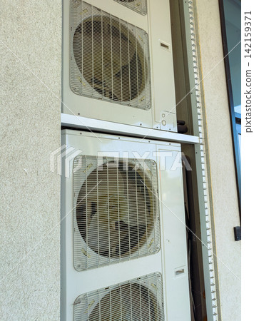 Fans are placed on a building wall in an outdoor area during daylight hours in a warm season Fans are placed on a building wall in an outdoor area during daylight hours in a warm season 142159371