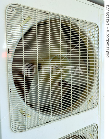 Cooling fan operates in a room during a hot day, spinning and providing a breeze to make the air comfortable for the people nearby Cooling fan operates in a room during a hot day, spinning and providing a breeze to make the air comfortable for the people nearby 142159372