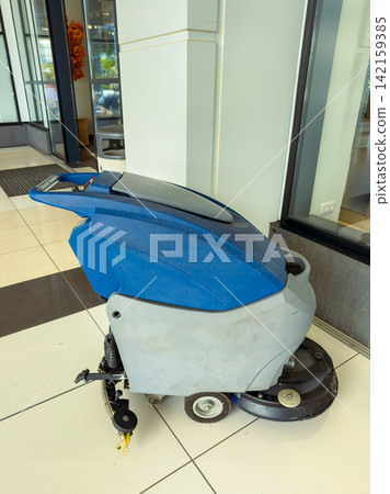 Cleaning machine is parked near the entrance of a modern building during daytime Cleaning machine is parked near the entrance of a modern building during daytime 142159385