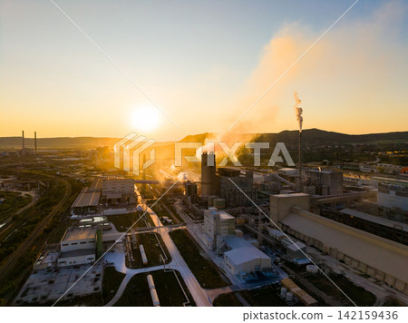 Sunset over an industrial area showing factories and smoke against the backdrop of a mountain range Sunset over an industrial area showing factories and smoke against the backdrop of a mountain range 142159436