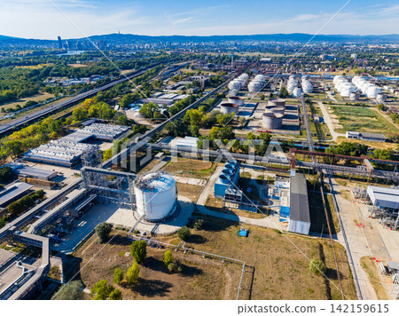 Industrial area with storage tanks and pipelines near a city skyline on a sunny day 142159615