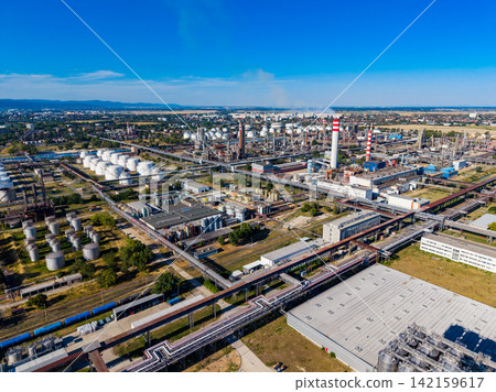 View of an industrial complex with storage tanks and smokestacks in the background during a clear day View of an industrial complex with storage tanks and smokestacks in the background during a clear day 142159617