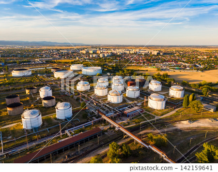 View of an oil storage facility with multiple tanks and surrounding urban area during sunset View of an oil storage facility with multiple tanks and surrounding urban area during sunset 142159641