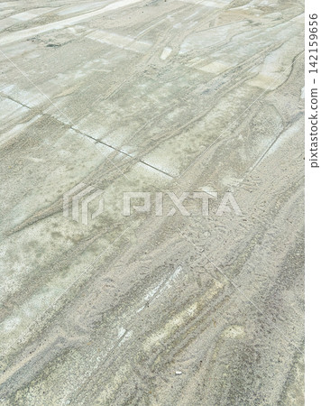 Ground covered with sand showing patterns from movement, taken during daylight in an outdoor location Ground covered with sand showing patterns from movement, taken during daylight in an outdoor location 142159656