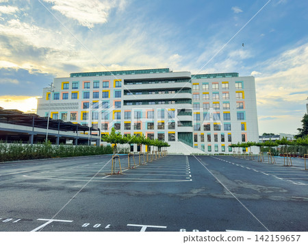 Modern building with colorful windows and empty parking lot during evening Modern building with colorful windows and empty parking lot during evening 142159657