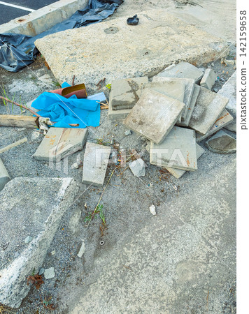 Construction debris is scattered on the ground near a road in a work zone during daylight hours Construction debris is scattered on the ground near a road in a work zone during daylight hours 142159658