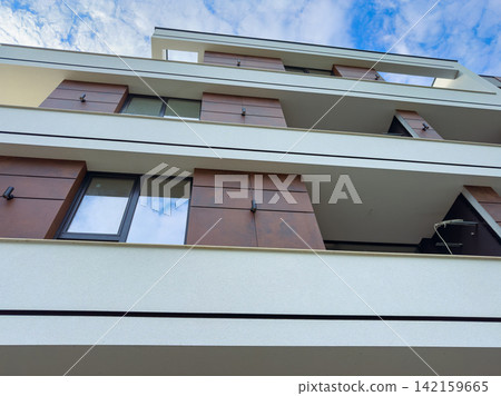 Modern building with balconies under a partly cloudy sky in an urban setting Modern building with balconies under a partly cloudy sky in an urban setting 142159665