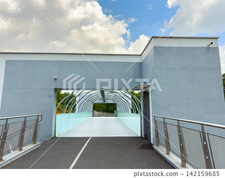 Walking through a modern bridge structure in a city under cloudy skies during the day Walking through a modern bridge structure in a city under cloudy skies during the day 142159685