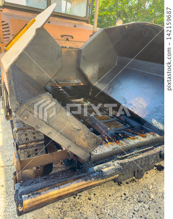 Construction machine is unloading material at a worksite in the daytime Construction machine is unloading material at a worksite in the daytime 142159687