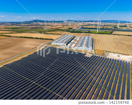 Solar panels and wind turbines in a large energy farm in a rural area during clear weather Solar panels and wind turbines in a large energy farm in a rural area during clear weather 142159748