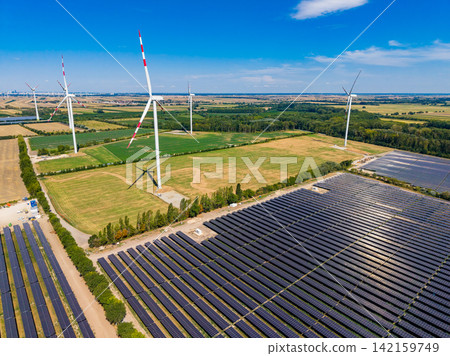 Wind turbines and solar panels on a farm in a rural area during a sunny day Wind turbines and solar panels on a farm in a rural area during a sunny day 142159749