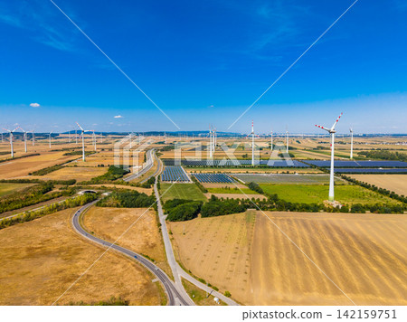 Wind turbines and solar panels in a landscape with clear blue sky during the day Wind turbines and solar panels in a landscape with clear blue sky during the day 142159751