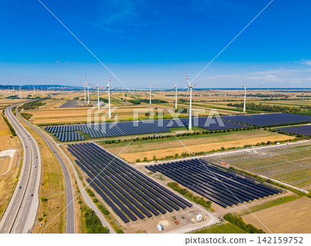 Wind turbines and solar panels in a large energy farm in a rural area during daytime Wind turbines and solar panels in a large energy farm in a rural area during daytime 142159752