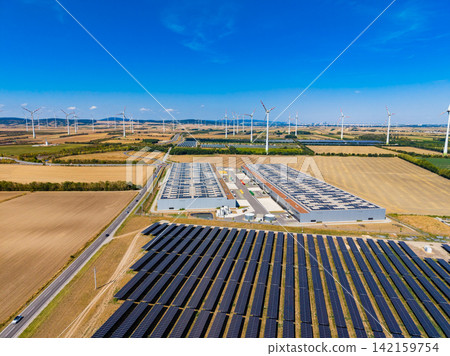 Solar panels and wind turbines in a large energy site under clear sky during daylight hours in rural area 142159754