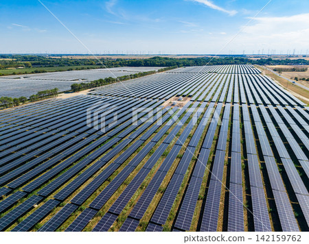 Large solar panel farm located in a flat area with rows of solar panels stretching into the distance during a clear day Large solar panel farm located in a flat area with rows of solar panels stretching into the distance during a clear day 142159762