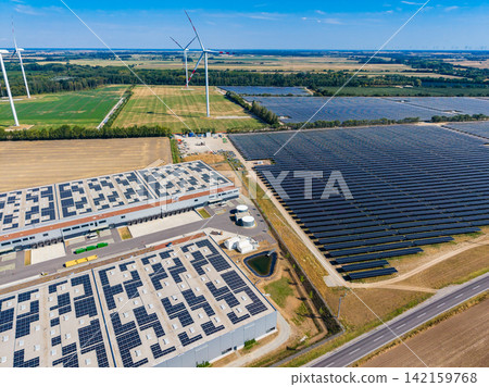 Solar panels and wind turbines are present in a large energy facility in an open area during daytime under clear skies Solar panels and wind turbines are present in a large energy facility in an open area during daytime under clear skies 142159768