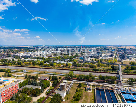 Industrial site in the daytime showing storage tanks, factories, and highways with blue sky and clouds Industrial site in the daytime showing storage tanks, factories, and highways with blue sky and clouds 142159773