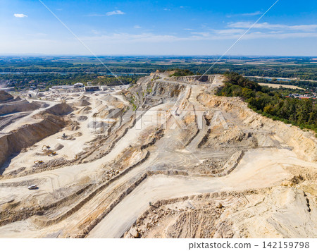 View of a limestone quarry in daylight showing heavy machinery and raw materials at work in the site View of a limestone quarry in daylight showing heavy machinery and raw materials at work in the site 142159798
