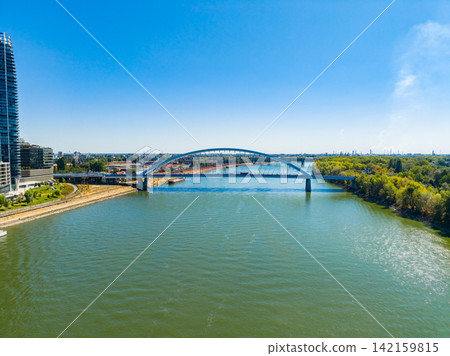 View of a river with a bridge and buildings during a clear day in an urban area View of a river with a bridge and buildings during a clear day in an urban area 142159815