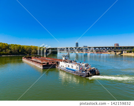 Barge moving under a bridge on a river in a bright day with clear blue sky Barge moving under a bridge on a river in a bright day with clear blue sky 142159832