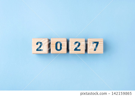 Wooden cubes with numbers of the New Year 2027 on a blue background Wooden cubes with numbers of the New Year 2027 on a blue background 142159865