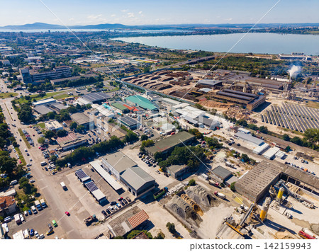 View of a city industrial area with buildings and construction sites near the waterfront during daytime View of a city industrial area with buildings and construction sites near the waterfront during daytime 142159943