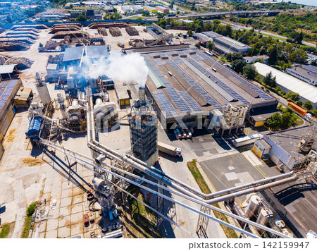 Industrial site with large buildings and machinery in operation during daylight Industrial site with large buildings and machinery in operation during daylight 142159947