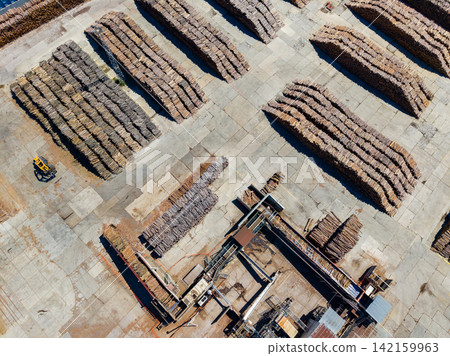 Wood storage area with organized stacks and machinery at a lumber yard during the day 142159963