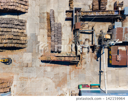 Wood processing facility located in a rural area with stacks of logs and machinery showing the process of handling timber Wood processing facility located in a rural area with stacks of logs and machinery showing the process of handling timber 142159964