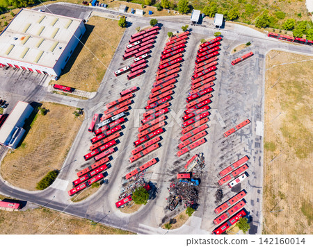 Bus parking lot with many red buses in a commercial area during a sunny day Bus parking lot with many red buses in a commercial area during a sunny day 142160014