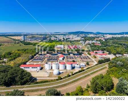 Industrial facility with tanks and processing areas near a city on a clear day in a rural setting Industrial facility with tanks and processing areas near a city on a clear day in a rural setting 142160022