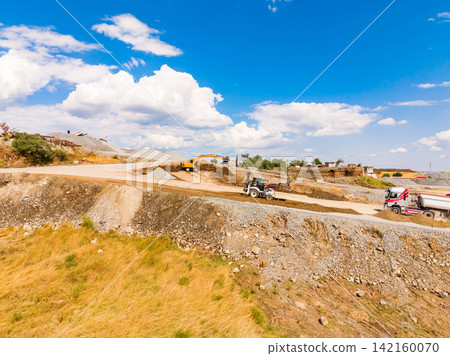 Granite quarry operations with heavy machinery under a clear blue sky in a busy work area Granite quarry operations with heavy machinery under a clear blue sky in a busy work area 142160070