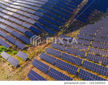 Solar panels cover a large area of land in a renewable energy field during daylight hours in a rural setting Solar panels cover a large area of land in a renewable energy field during daylight hours in a rural setting 142160093