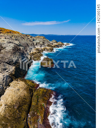 Coastline with rocks and blue water under clear sky in daytime Coastline with rocks and blue water under clear sky in daytime 142160145