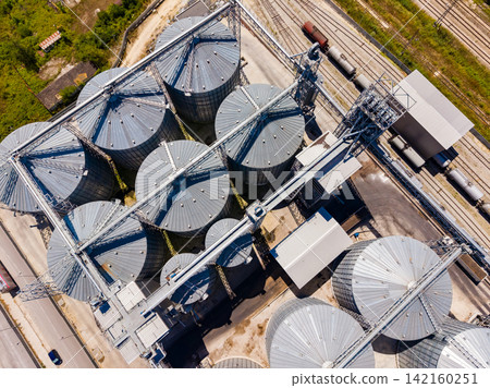 Storage silos are seen from above with trains in the background during the day in an industrial area Storage silos are seen from above with trains in the background during the day in an industrial area 142160251