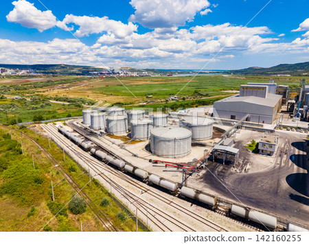 Industrial site with storage tanks and rail cars under blue sky Industrial site with storage tanks and rail cars under blue sky 142160255