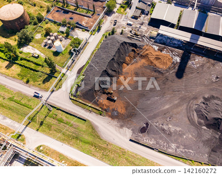 View of an industrial site with storage areas, vehicles, and machinery during daytime in an outdoor setting 142160272