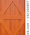 Close up of a rustic wood plank door painted in bright orange brown. 142160807