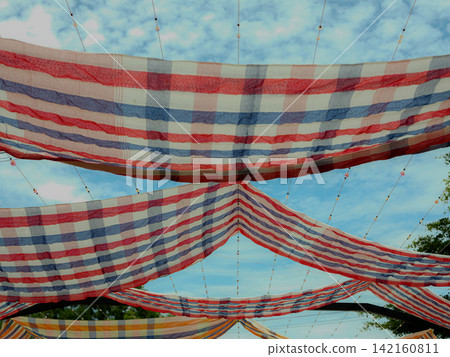 Colorful pha khao ma fabrics used as sunshade awning in a cultural festival. Colorful pha khao ma fabrics used as sunshade awning in a cultural festival. 142160811