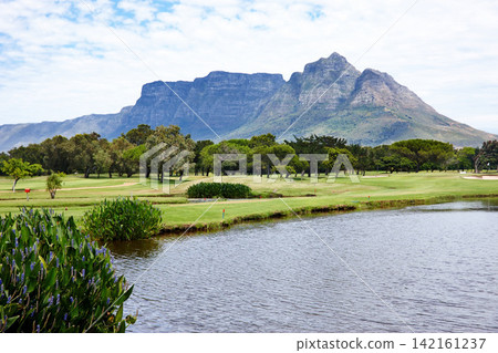 Mountain, landscape and water with grass at golf course in summer on holiday or vacation. Calm, morning and lake with turf field for sport in woods, forest or nature of park with trees and plants Mountain, landscape and water with grass at golf course in summer on holiday or vacation. Calm, morning and lake with turf field for sport in woods, forest or nature of park with trees and plants 142161237